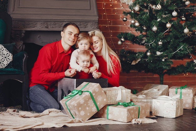 Familia sentada en casa cerca del árbol de navidad