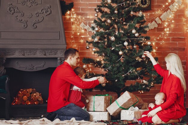 Familia sentada en casa cerca del árbol de navidad