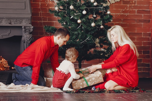 Familia sentada en casa cerca del árbol de navidad