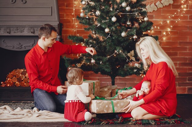 Familia sentada en casa cerca del árbol de navidad