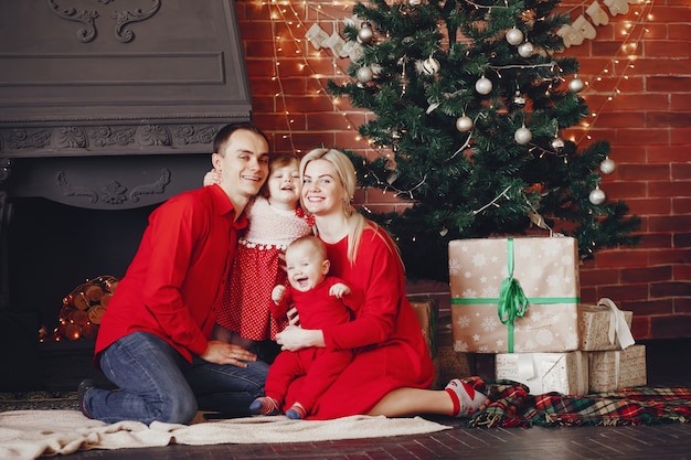 Familia sentada en casa cerca del árbol de navidad