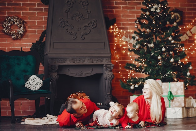 Familia sentada en casa cerca del árbol de navidad