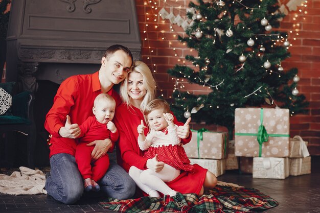 Familia sentada en casa cerca del árbol de navidad