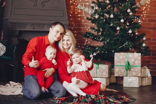 Familia sentada en casa cerca del árbol de navidad