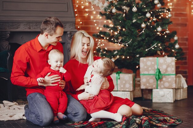 Familia sentada en casa cerca del árbol de navidad