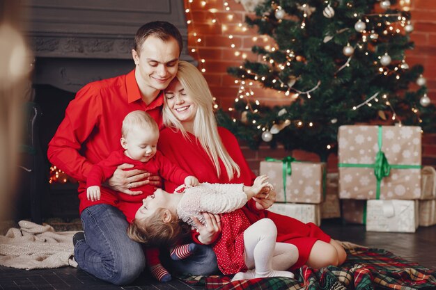 Familia sentada en casa cerca del árbol de navidad