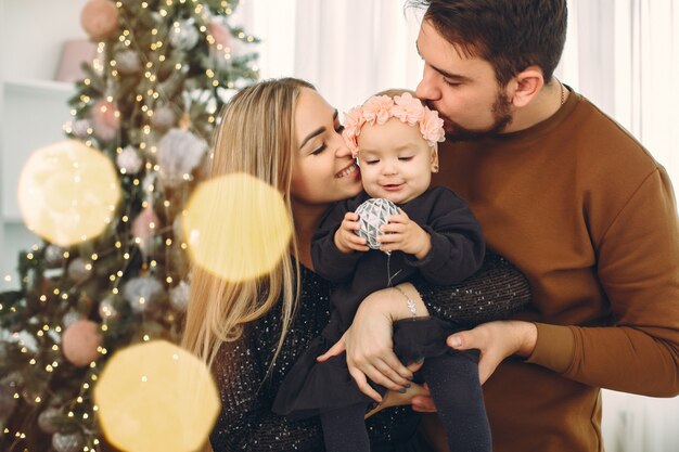 Familia sentada en casa cerca del árbol de navidad