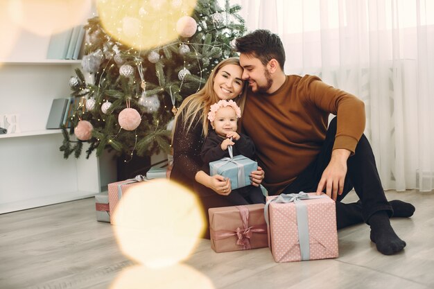 Familia sentada en casa cerca del árbol de navidad