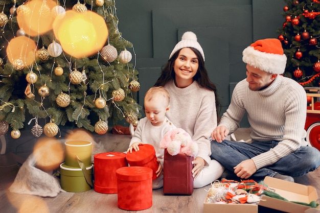 Familia sentada en casa cerca del árbol de navidad