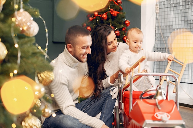 Familia sentada en casa cerca del árbol de navidad