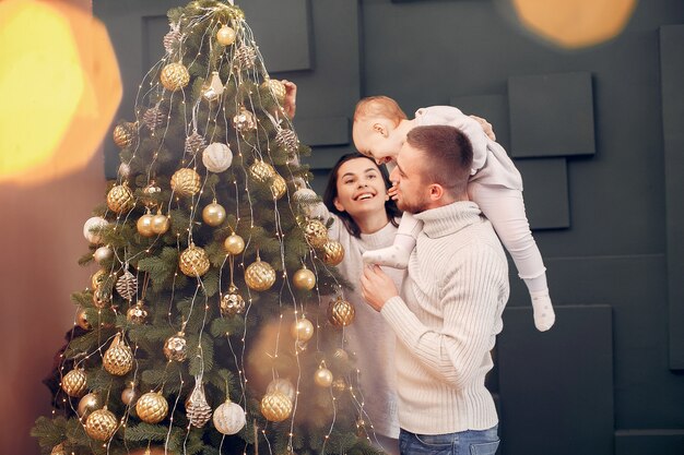 Familia sentada en casa cerca del árbol de navidad