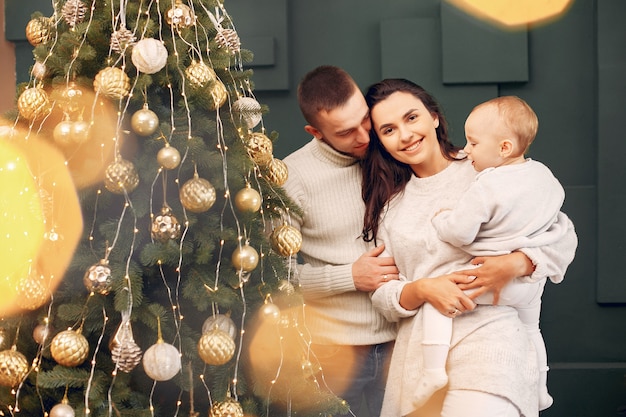 Familia sentada en casa cerca del árbol de navidad