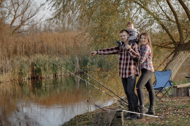 Foto gratuita familia sentada cerca del río en una mañana de pesca