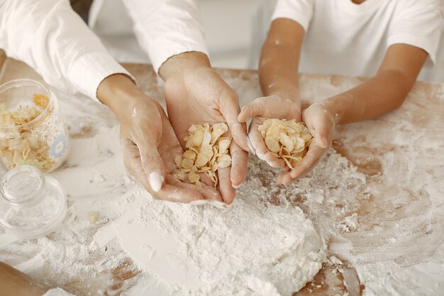 Familia sentada en una cocina y cocinar la masa para galletas