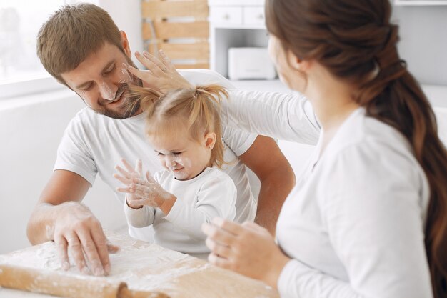 Familia sentada en una cocina y cocinar la masa para galletas