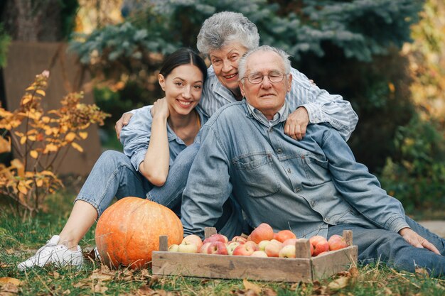 Familia sentada en un jardín con manzanas y calabaza