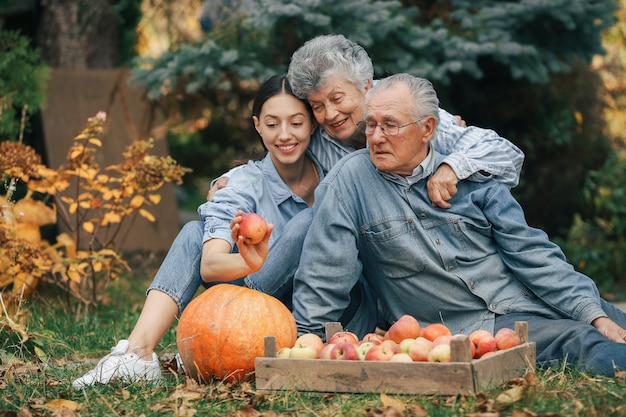 Familia sentada en un jardín con manzanas y calabaza