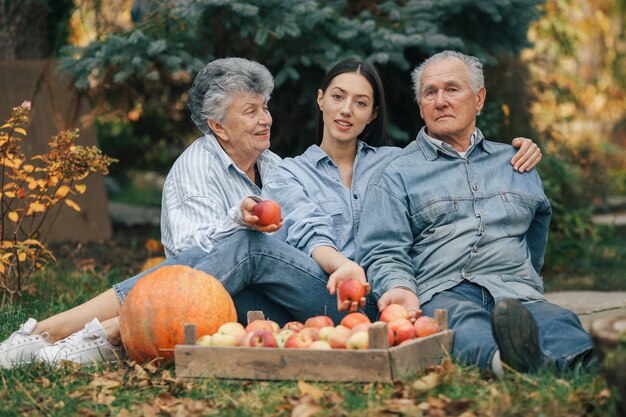 Familia sentada en un jardín con manzanas y calabaza