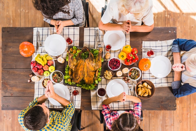 Familia sentada a la mesa y rezando