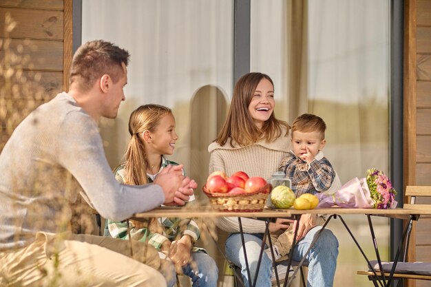 Familia sentada a la mesa en la veranda de la casa