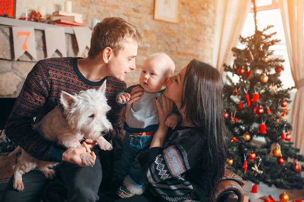 Familia sentada en un sofá con el perro en navidad