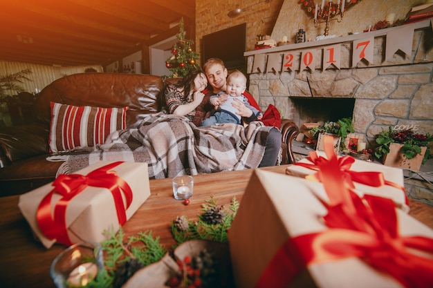 Familia sentada en un sofá vista a través de regalos marrones con lazos rojos