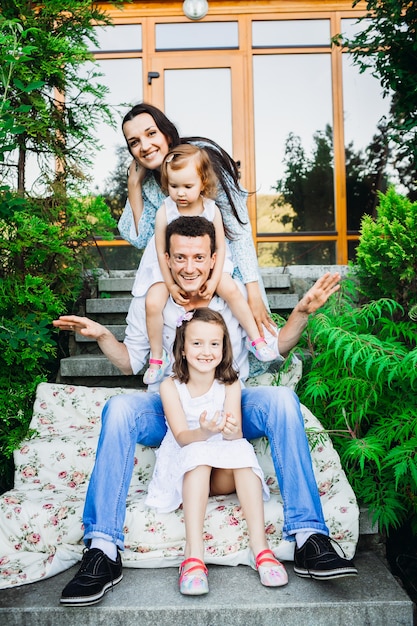 Foto gratuita la familia se sienta en la fila en pasos antes de la casa