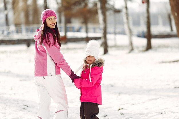 Familia con sombreros de invierno tejidos en vacaciones familiares de Navidad. Mujer y niña en un parque. Gente jugando.