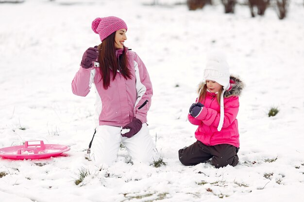 Familia con sombreros de invierno tejidos en vacaciones familiares de Navidad. Mujer y niña en un parque. Gente jugando.