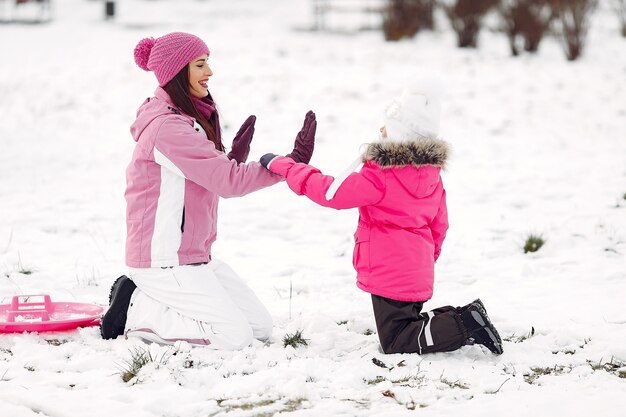 Familia con sombreros de invierno tejidos en vacaciones familiares de Navidad. Mujer y niña en un parque. Gente jugando.