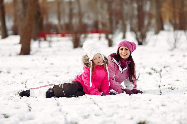 Familia con sombreros de invierno tejidos en vacaciones familiares de Navidad. Mujer y niña en un parque. Gente jugando.