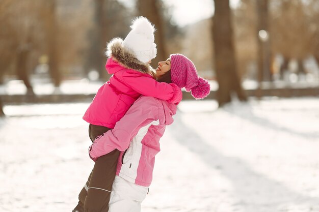 Familia con sombreros de invierno tejidos en vacaciones familiares de Navidad. Mujer y niña en un parque. Gente jugando.