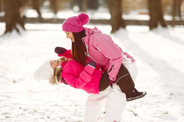 Familia con sombreros de invierno tejidos en vacaciones familiares de Navidad. Mujer y niña en un parque. Gente jugando.