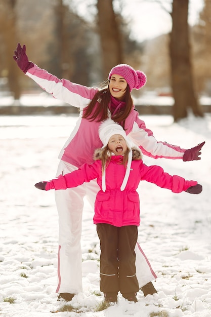 Familia con sombreros de invierno tejidos en vacaciones familiares de Navidad. Mujer y niña en un parque. Gente jugando.