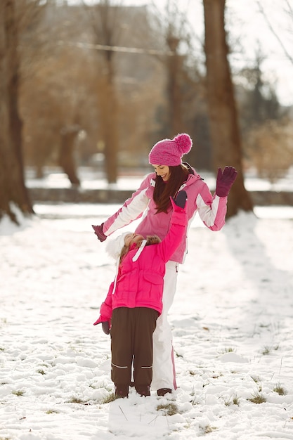 Familia con sombreros de invierno tejidos en vacaciones familiares de Navidad. Mujer y niña en un parque. Gente jugando.