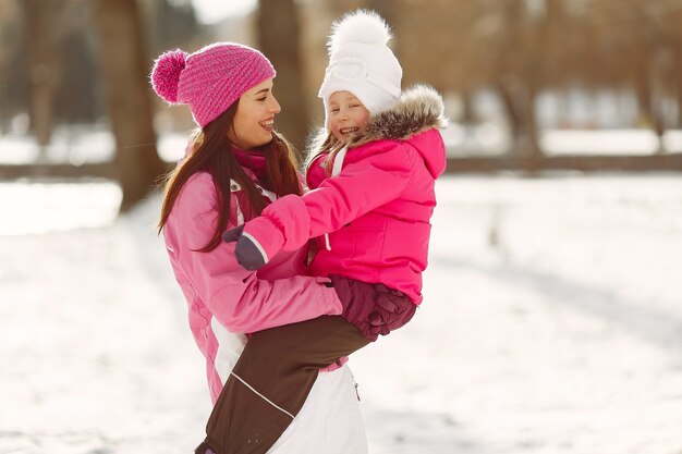 Familia con sombreros de invierno tejidos en vacaciones familiares de Navidad. Mujer y niña en un parque. Gente jugando.