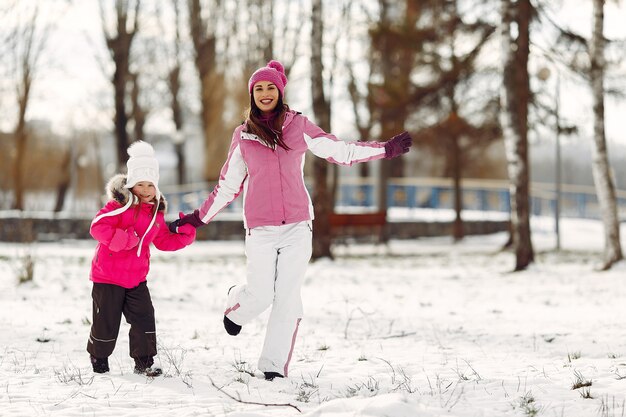 Familia con sombreros de invierno tejidos en vacaciones familiares de Navidad. Mujer y niña en un parque. Gente jugando.