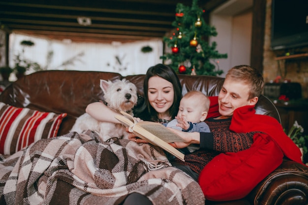 Familia sonriendo en un sofá con un libro en las manos del padre