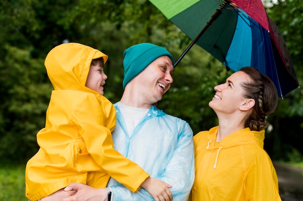 Familia sonriendo bajo su paraguas