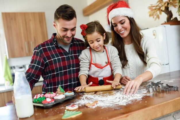 Familia sonriente decorando las galletas de navidad en la cocina