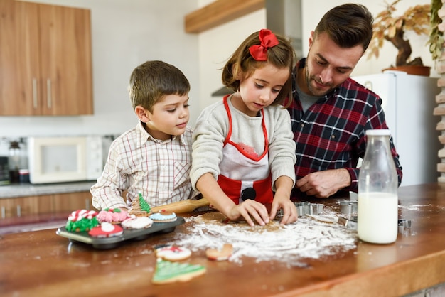 Familia sonriente decorando las galletas de navidad en la cocina