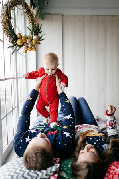 Familia sonriente feliz en el estudio en el fondo del árbol de navidad con el regalo