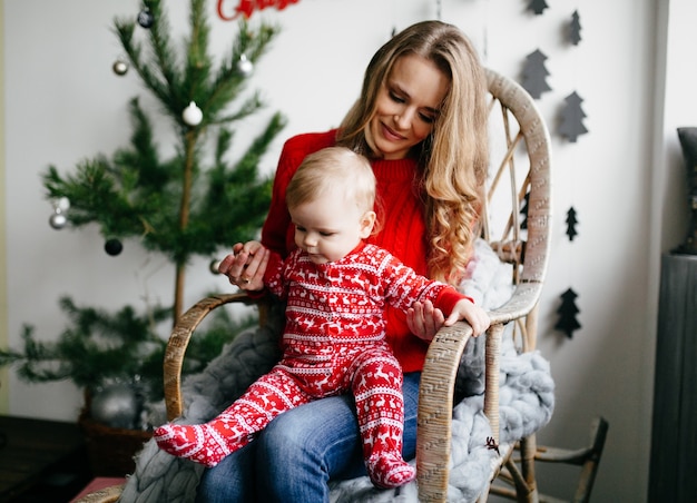 Familia sonriente feliz en el estudio en el fondo del árbol de navidad con el regalo