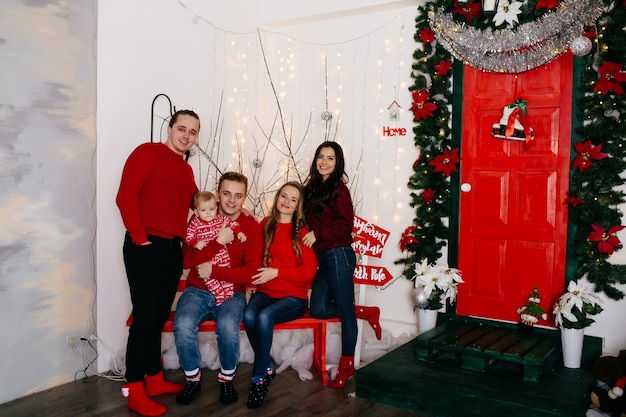 Familia sonriente feliz en el estudio en el fondo del árbol de navidad con el regalo