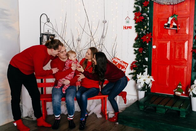 Familia sonriente feliz en el estudio en el fondo del árbol de navidad con el regalo