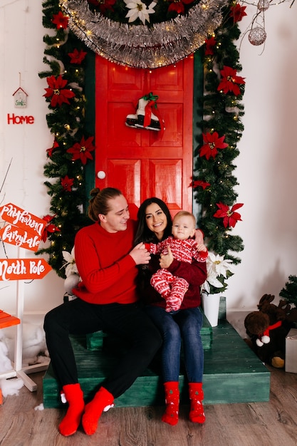 Familia sonriente feliz en el estudio en el fondo del árbol de navidad con el regalo