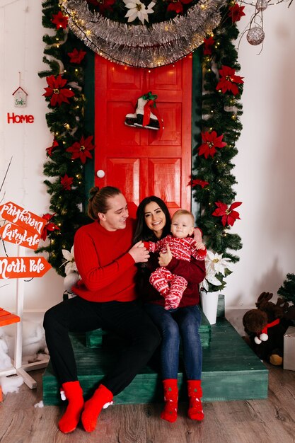 Familia sonriente feliz en el estudio en el fondo del árbol de navidad con el regalo