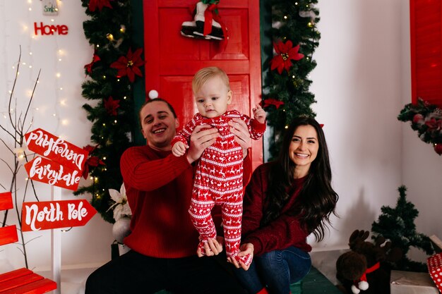 Familia sonriente feliz en el estudio en el fondo del árbol de navidad con el regalo