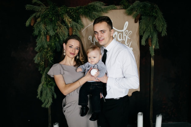 Foto gratuita familia sonriente feliz en el estudio en el fondo del árbol de navidad con el regalo