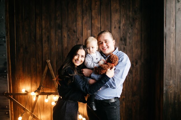 Familia sonriente feliz en el estudio en el fondo del árbol de navidad con el regalo